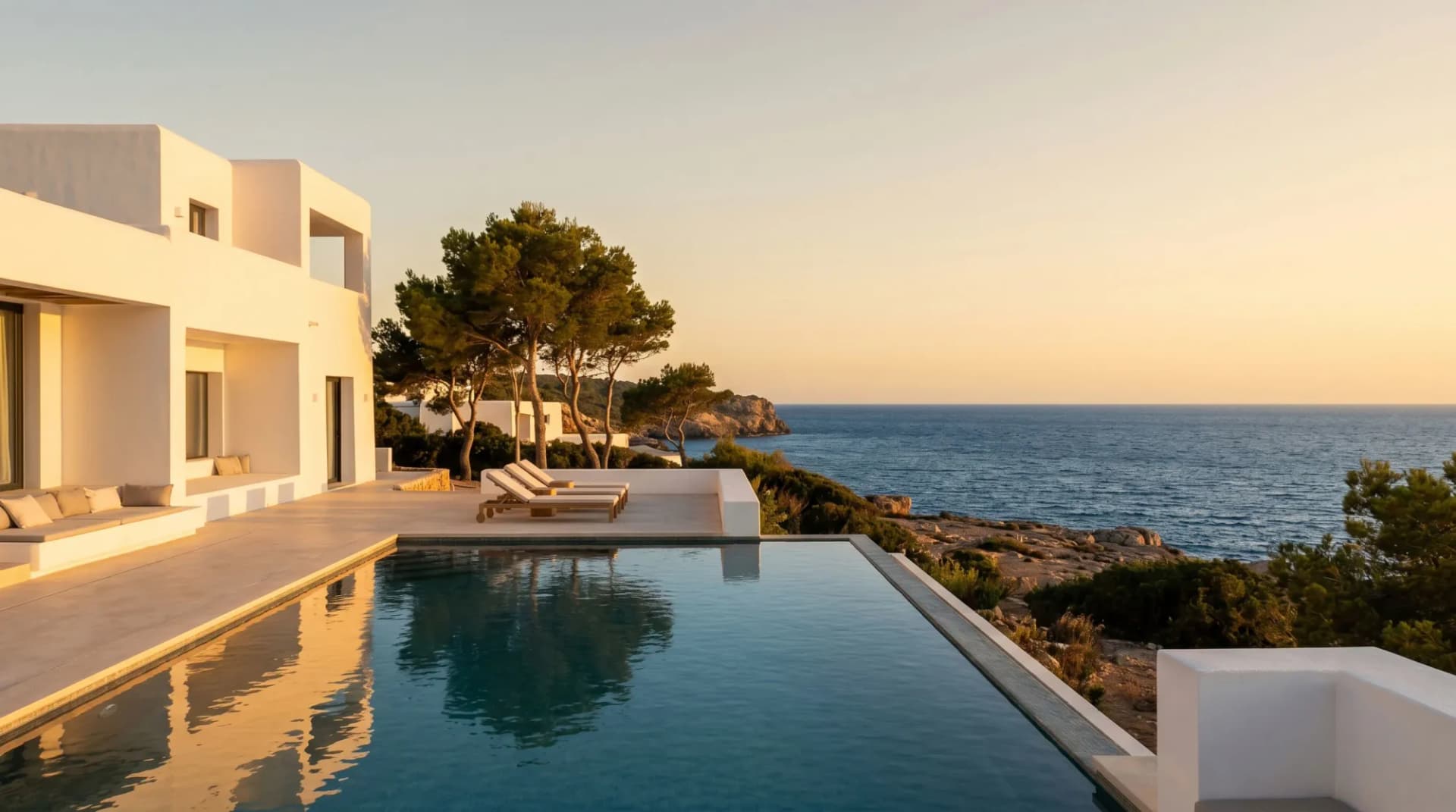 Whitewashed luxury villa with an infinity pool overlooking the Mediterranean coastline at sunset in Ibiza, Spain